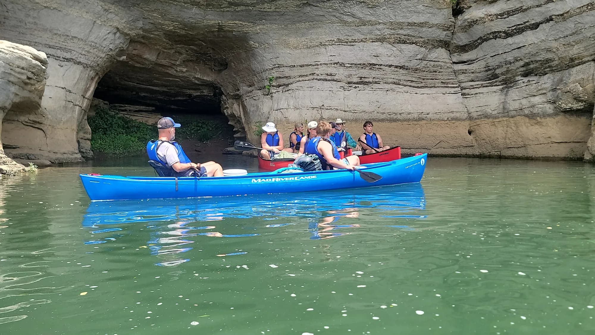Canoes gliding beneath a towering river bluff