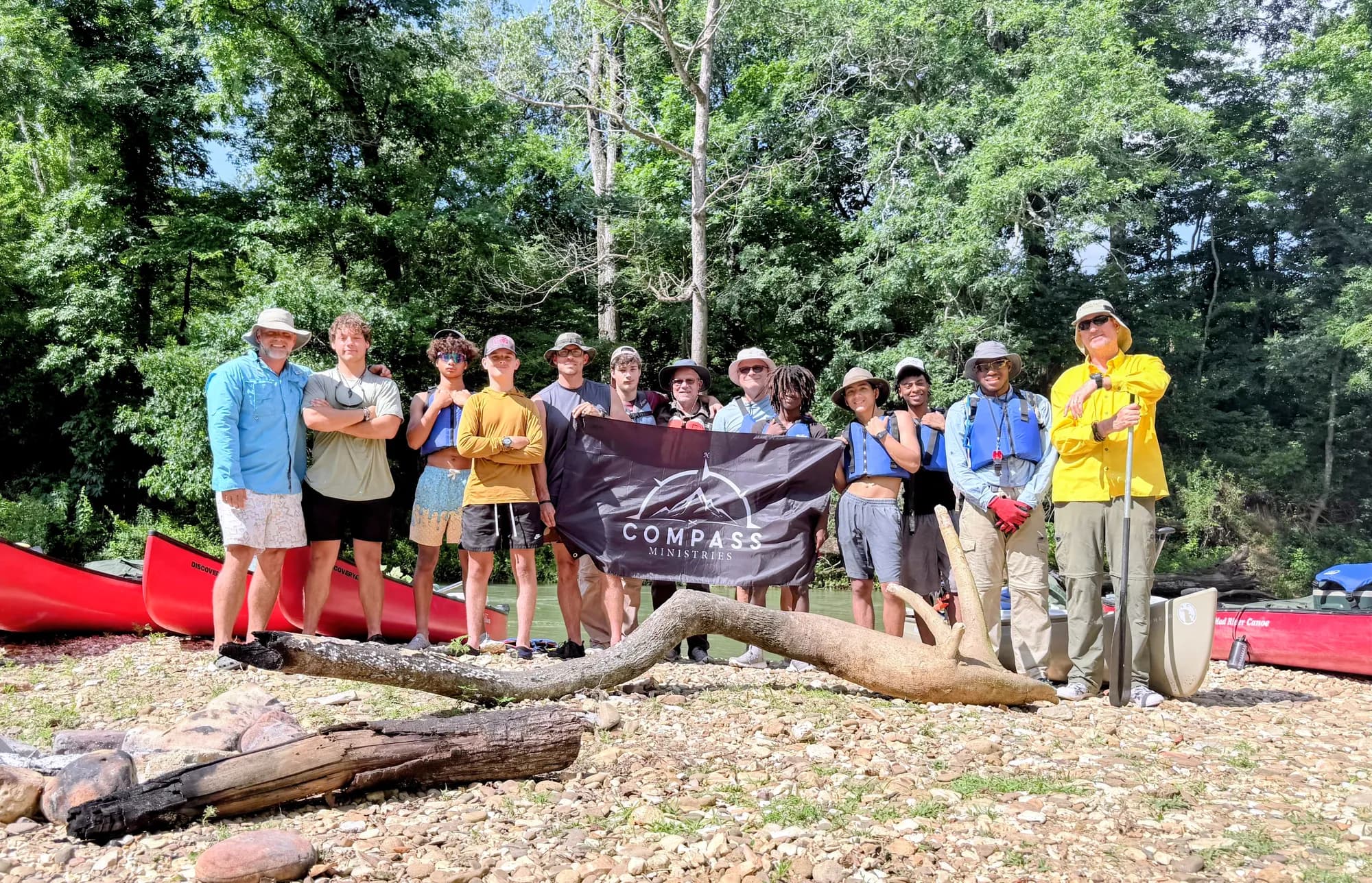 The crew gathered with a Compass Outdoors banner on the riverbank